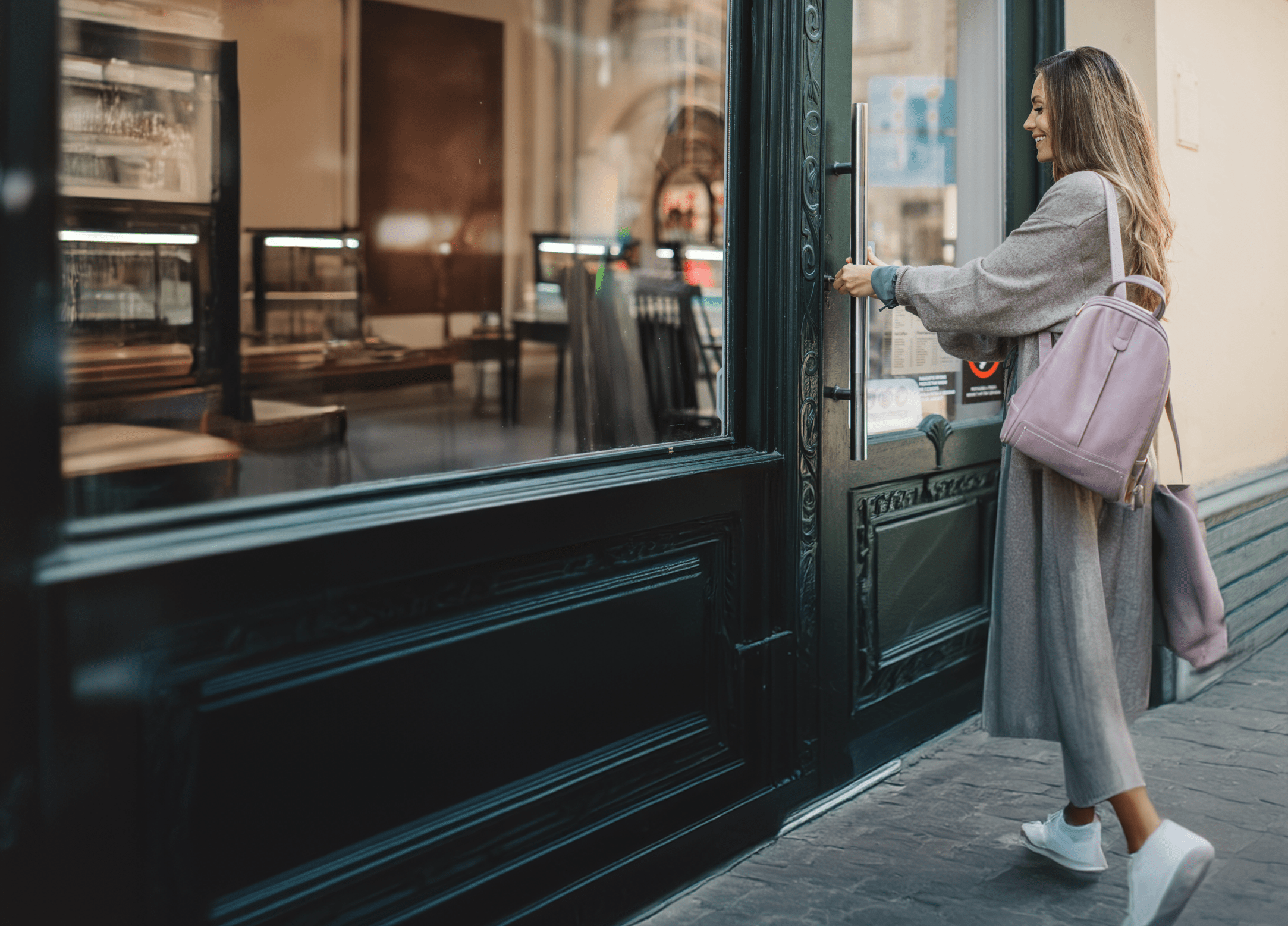 A young woman opens the door of her shop with a key