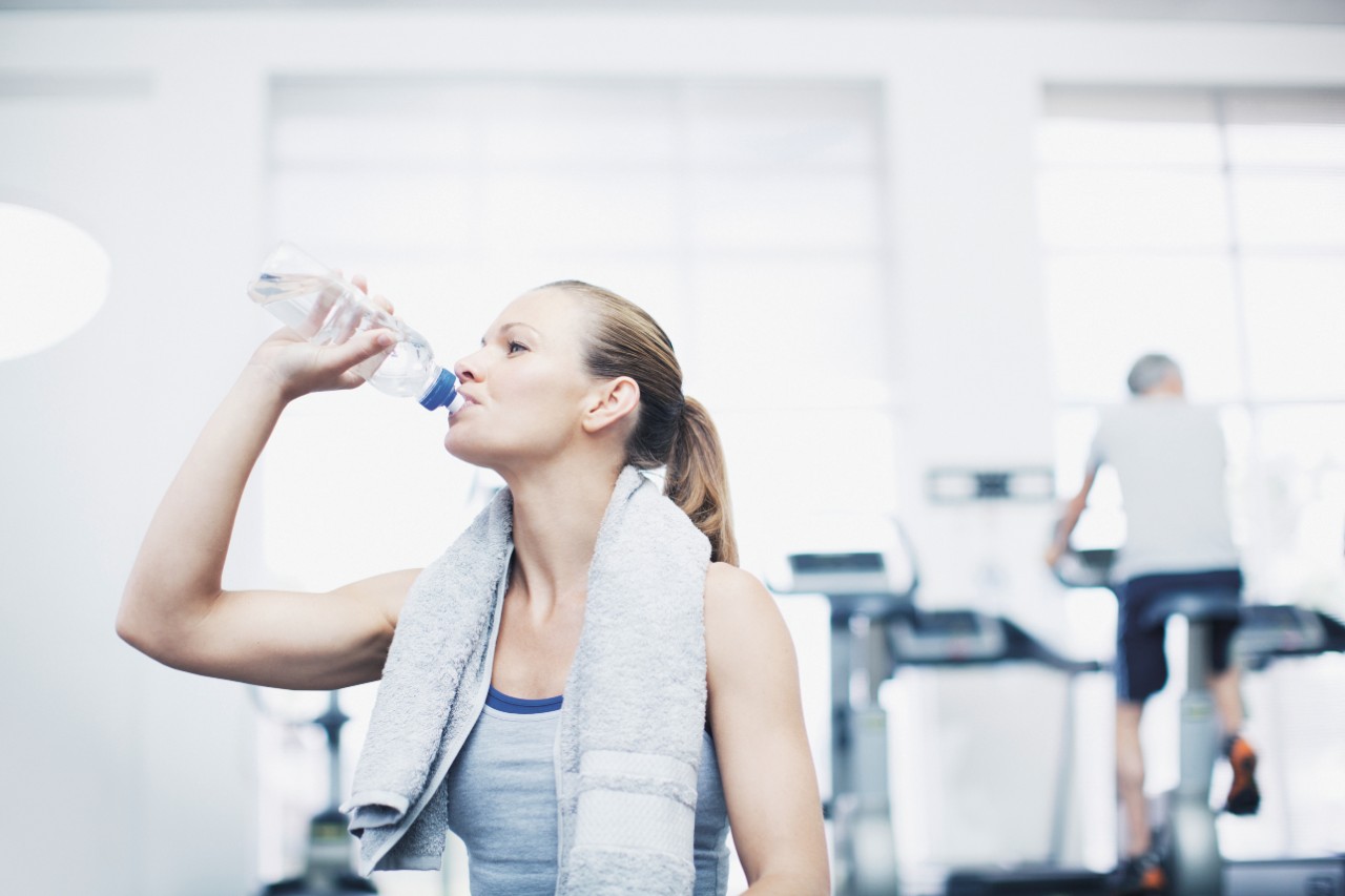 a girl drinking bottled water in a gym