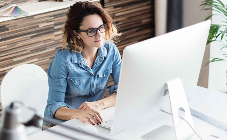 woman sitting down in her office while facing her desktop