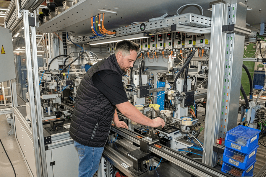 Instandhalter bei DOM Sicherheitstechnik wartet und justiert eine automatisierte Fertigungsanlage und sorgt für einen reibungslosen Produktionsablauf.