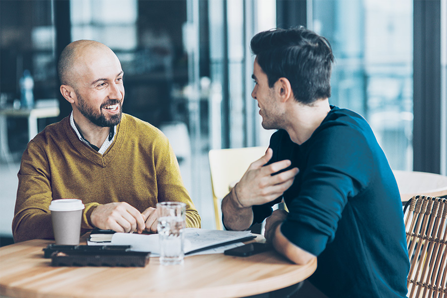 zwei Männer unterhalten sich in einem Café über Geschäftliches