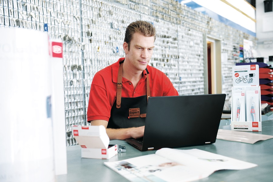 Locksmith sitting in his shop using a laptop