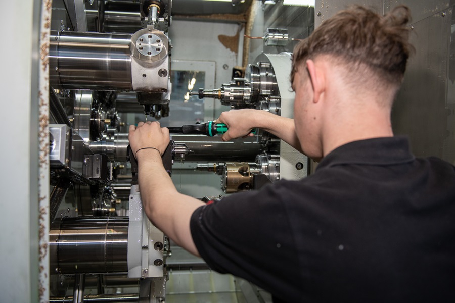 Cutting machine operator apprentice at DOM Security setting up a CNC machine and performing precision machining on metal components.