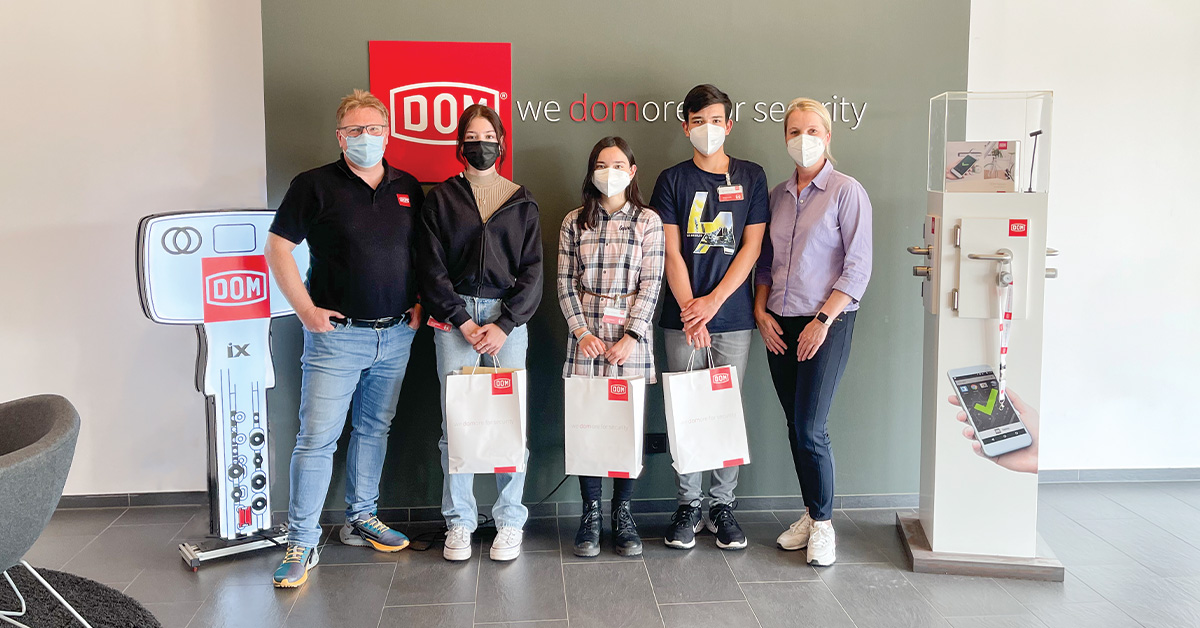 The trainees stand together with two colleagues from DOM in the foyer of the company headquarters in Brühl.