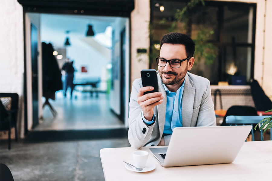 a man looking at his smartphone in a cafe while smiling