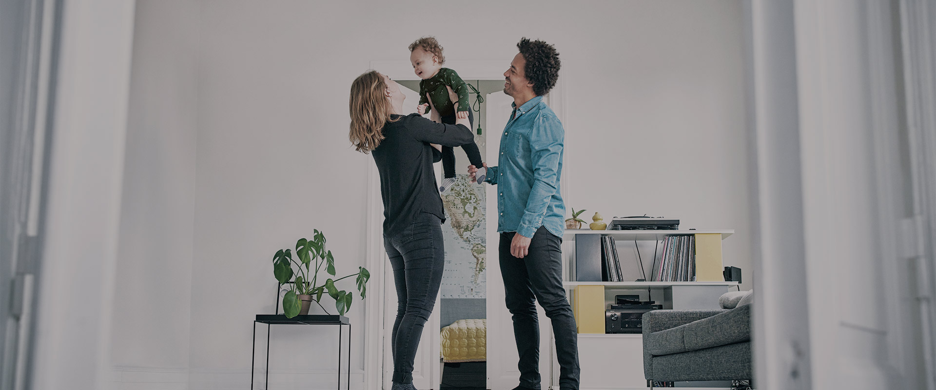 Mom holding her son in her arms while smiling together with dad in the living room at home
