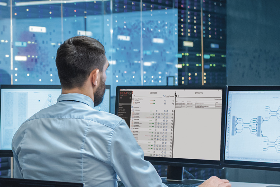 a person in front of computer screens looking at DOMPloy interface