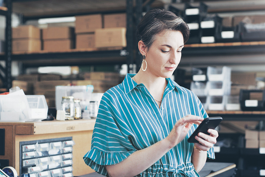 a woman holding her smartphone in a small warehouse