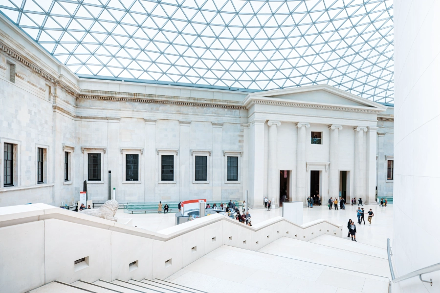 Interior of a historic building with a large glass roof and visitors in the main hall.