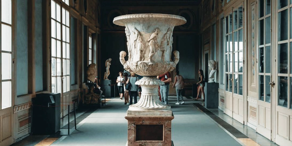 Visitors at the Uffizi Gallery in front of a large carved ancient vase.