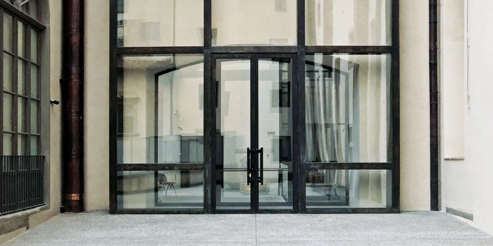 Modern glass entrance to the Uffizi Gallery with reflections of historic architecture.