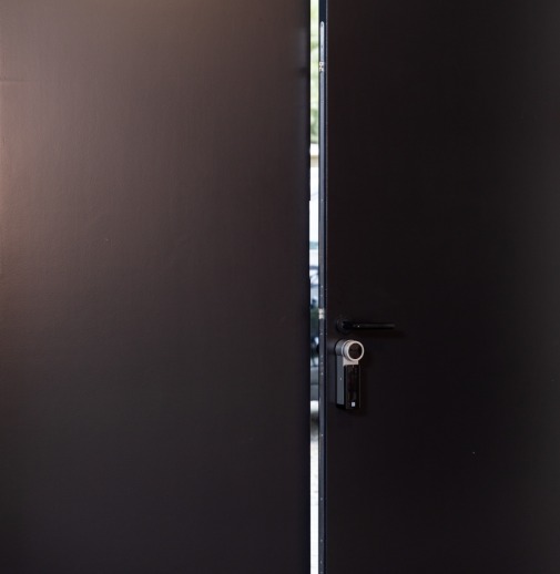 a black door ajar protected by DOM Roq smart lock