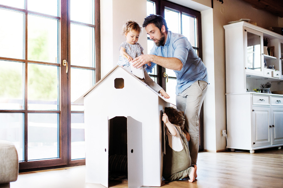 dad and daughters playing with a cardboard house