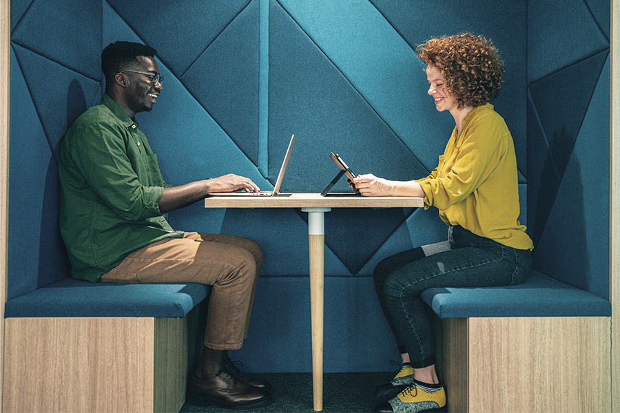 a smiling boy and girl sitting across from each other at a hot desk station
