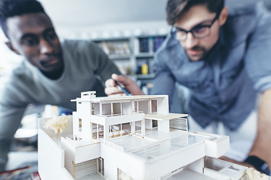two architects work on a model of a building