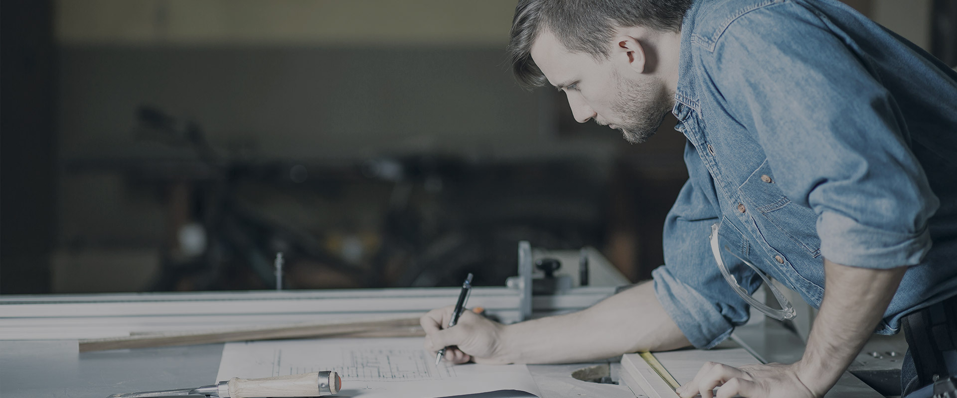 a carpenter writing wood dimension on a piece of paper next to a bunch of cutted woodwork