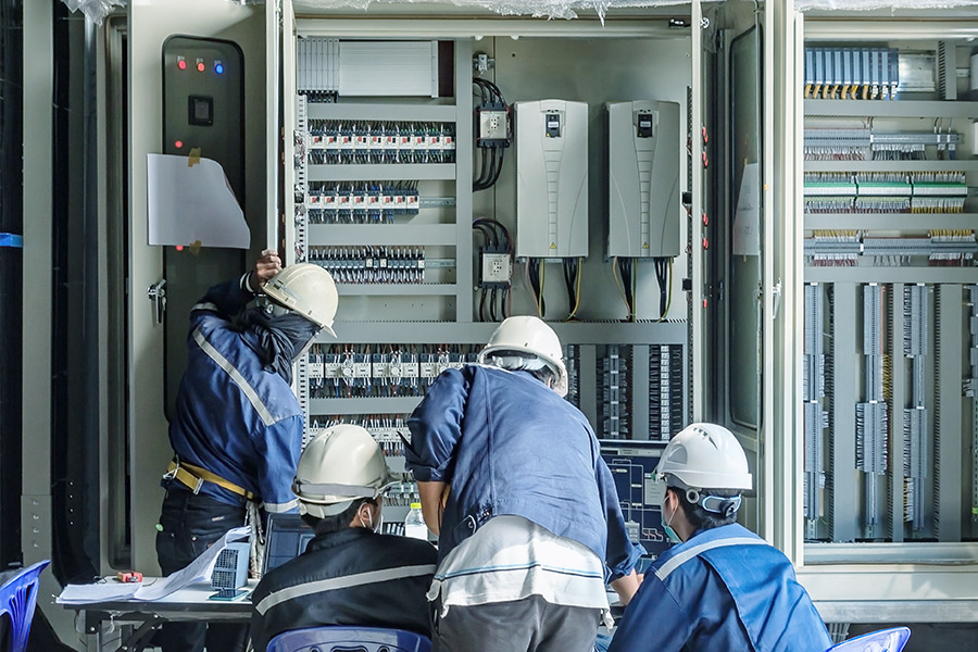 quattro operatori effettuano dei lavori di manutenzione a un quadro elettrico