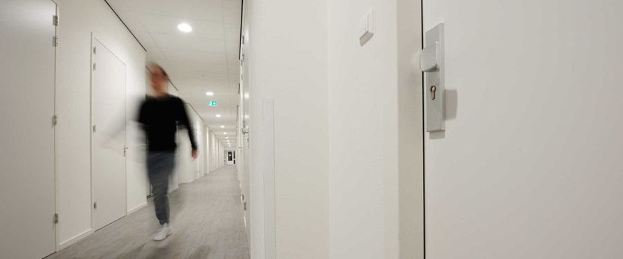 man walking through a hallway, focus on a door
