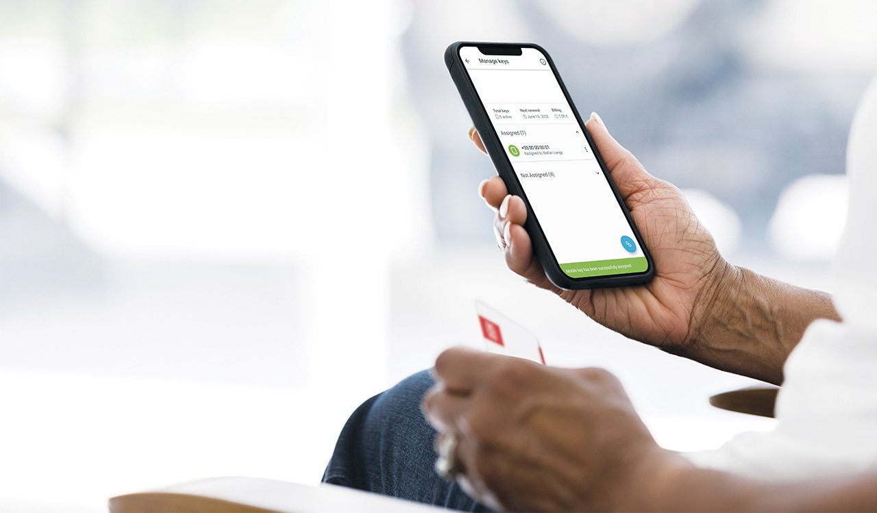 Vrouw houdt smartphone vast met DOM Key App en NFC kaart